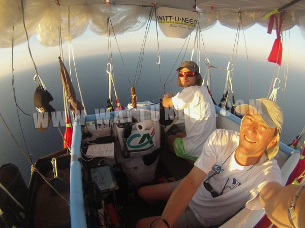 Hervé Moine et Eric Decellieres en vol sur un ballon équipé de panneaux solaires au milieu des nuages avec le logo Wattuneed.