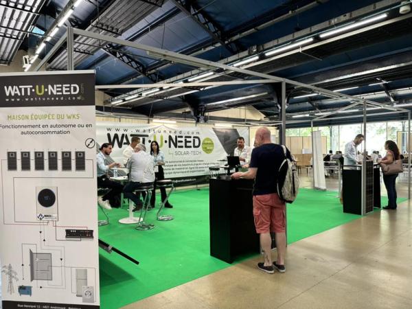 Wattuneed booth at Survival Expo – Autonomy & Outdoor: Vivre Autonome, the Sustainable Home Fair, with customers, Wattuneed employees, and Wattuneed products including solar panels and inverters